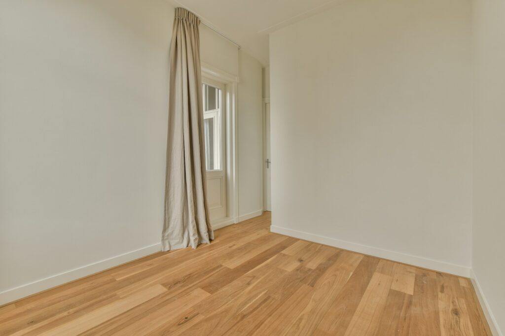 a room with wood flooring and a curtain in